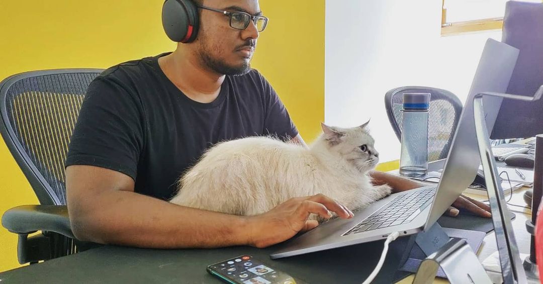 Dani Akash coding at his desk with a cat on his lap